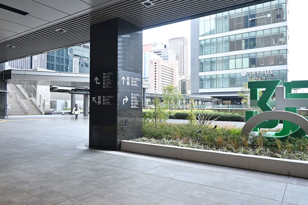 【バルチカ03 行き方】駅の通路から見た建物と緑の植栽、案内表示