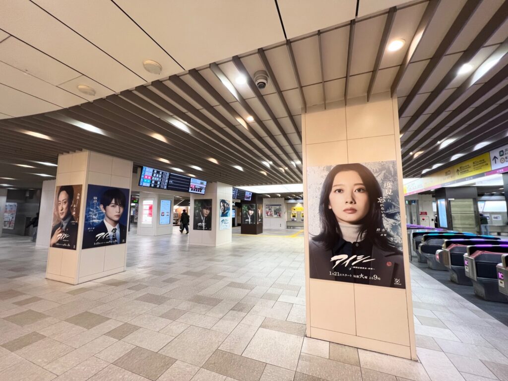 【アイシー ロケ地】駅の地下通路にある改札前でドラマアイシーのポスターが複数並び右側に飯豊まりえの大きなポスター