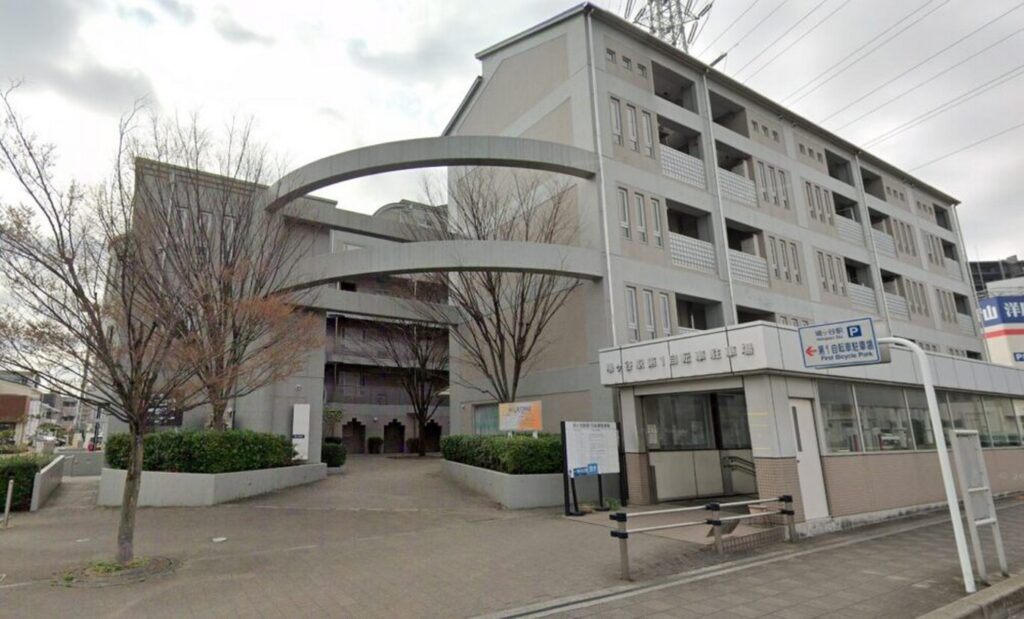 【アイシー ロケ地】アーチ型連絡通路がある灰色の建物と城ヶ崎駅方面の案内看板