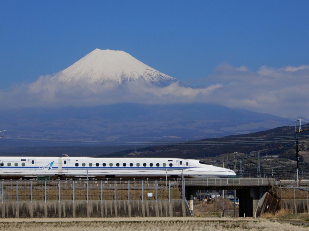 【富士山新幹線】雪化粧をした富士山を背景に白い新幹線が橋を走行