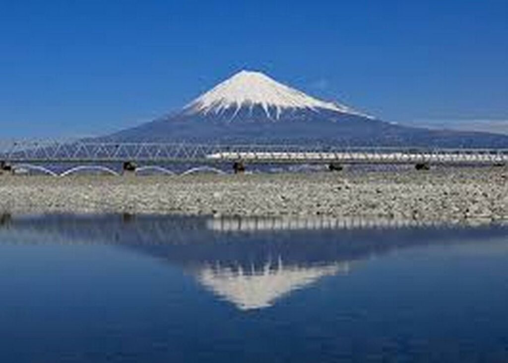【富士山新幹線】雪をかぶった富士山と橋を渡る新幹線が青空の下水面に映る景色