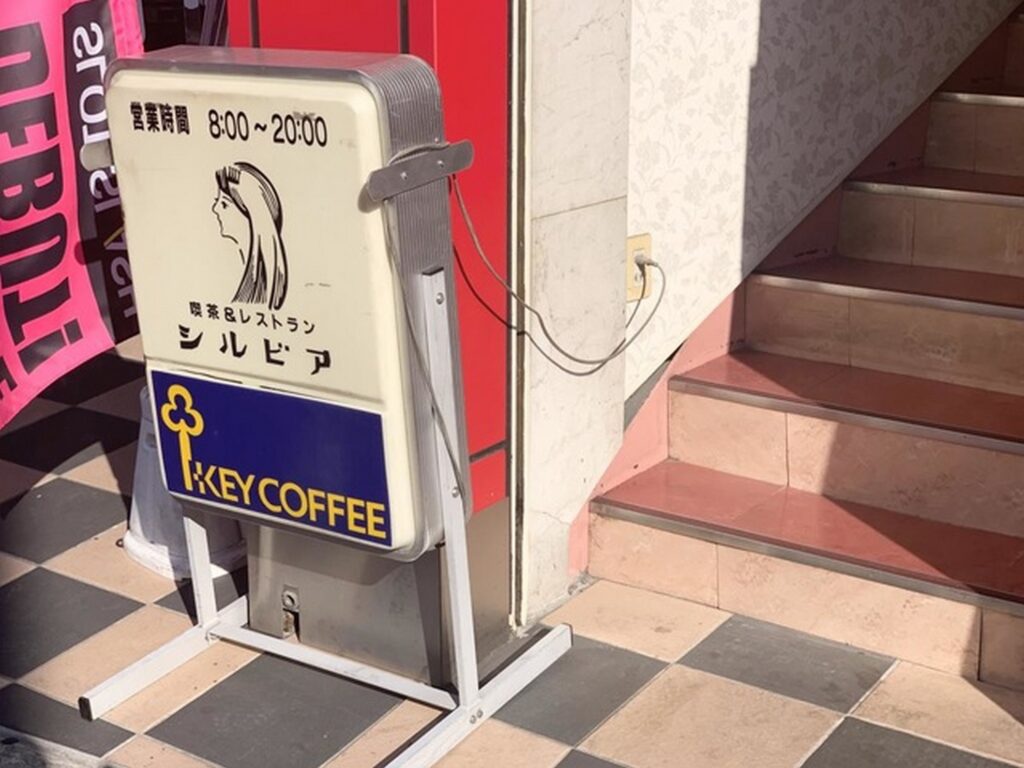 【春になったらロケ地】喫茶レストランシルビアの立て看板営業時間8時から20時女性のイラストとキーコーヒーの文字