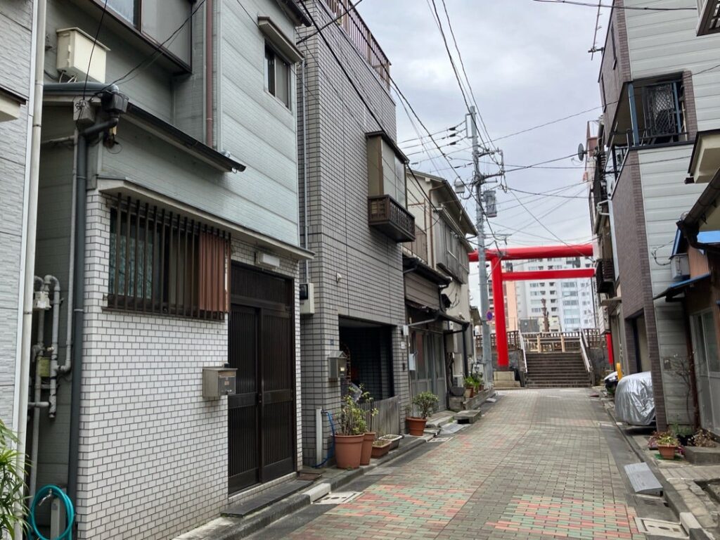 【春になったらロケ地】建物が並ぶ路地の先に赤い鳥居と神社の階段がある日本の風景