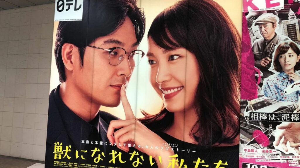 【けものになれない私たちロケ地】ドラマ けものになれない私たち の宣伝ポスターで 笑顔の女性が男性の唇に指をあてている