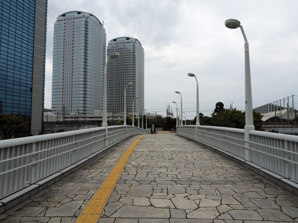 【歩道橋 ロケ地】白い手すりの歩道橋と高層ビル群曇り空の都市風景