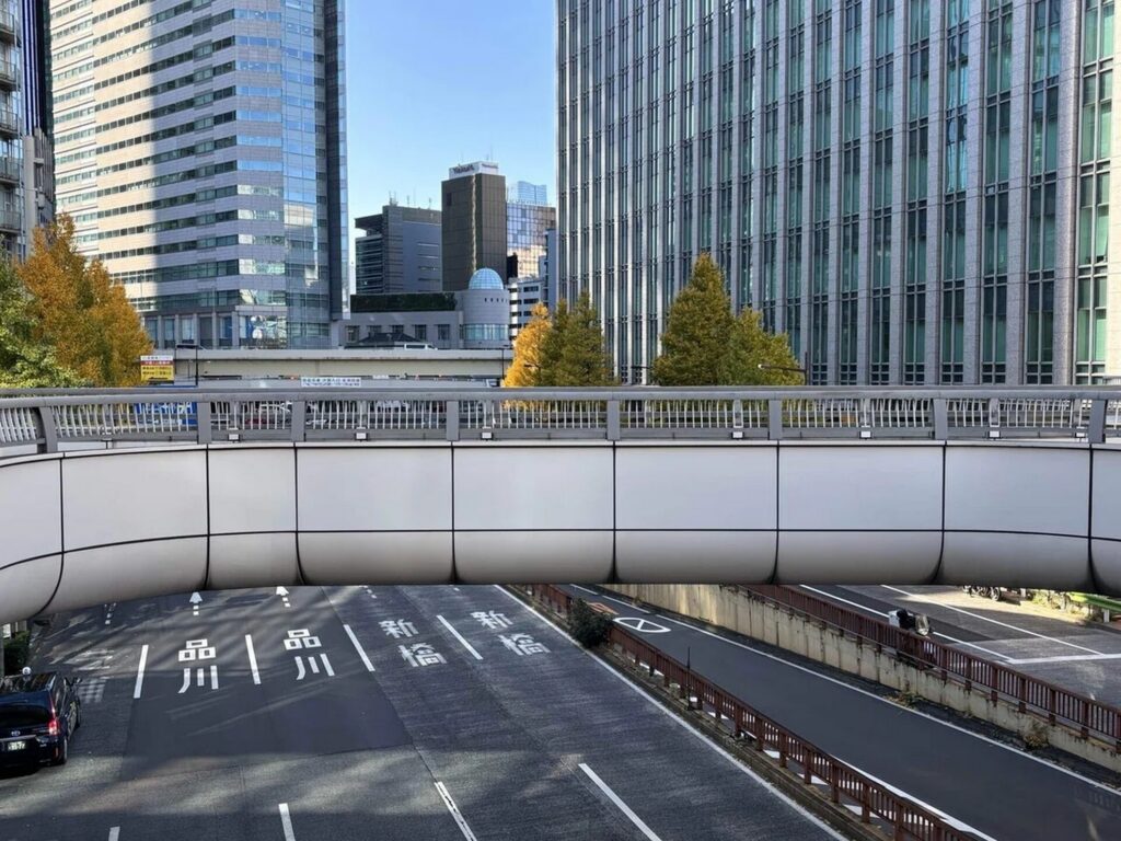 【歩道橋 ロケ地】晴れた都市の風景 品川と新橋へ向かう車道の上の湾曲した白い歩道橋と複数の高層ビル