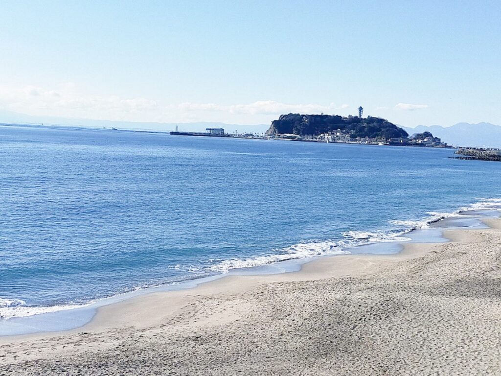 【うみまちダイアリーロケ地】青い海と砂浜の先に江の島が見える風景