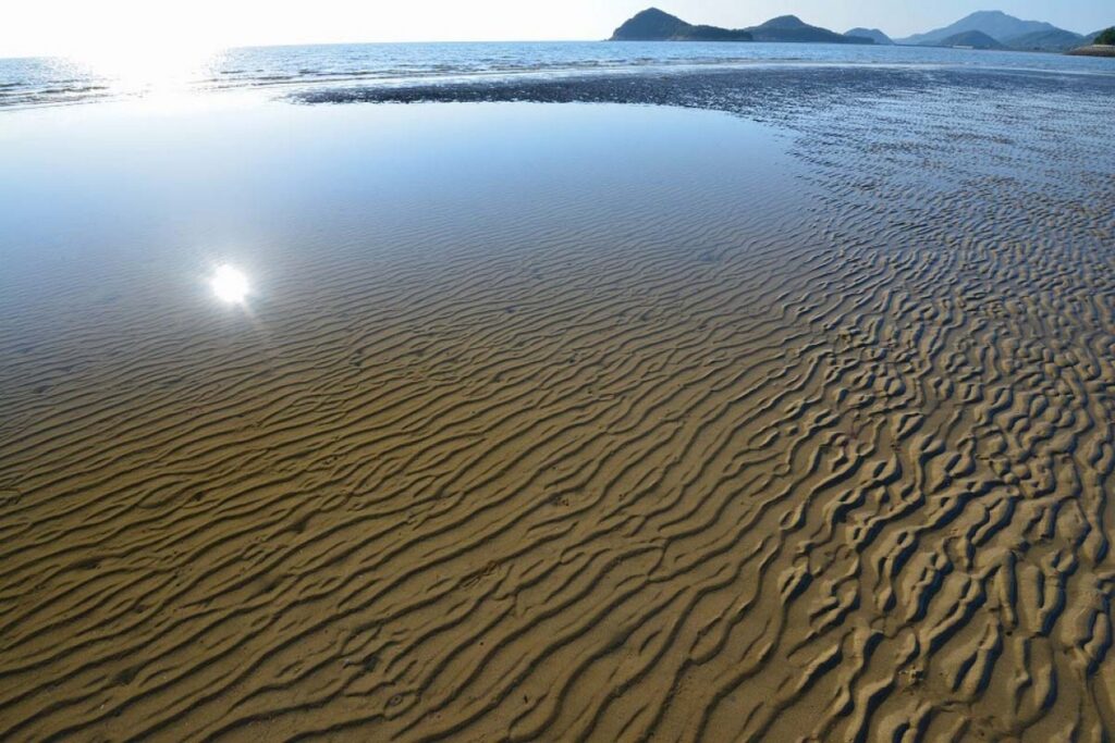 【Chichibugahama Beach】A calm beach with sand patterns and sunlight reflecting on the water surface