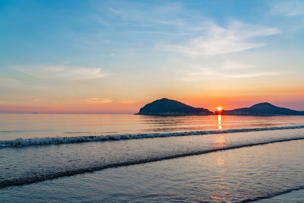 【Chichibugahama Beach】Sunset over the ocean with a small island and waves on the shore