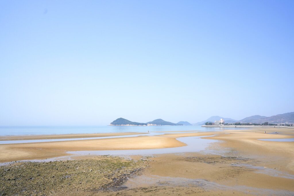 【Chichibugahama Beach】A beautiful sandy beach with shallow water and mountains in the background on a sunny day