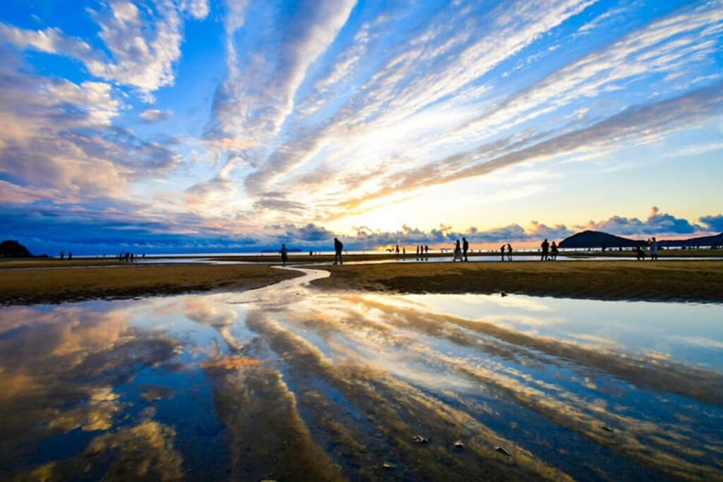 【Chichibugahama Beach】A beautiful beach scene with people walking on the wet sand reflecting the colorful sky at sunset