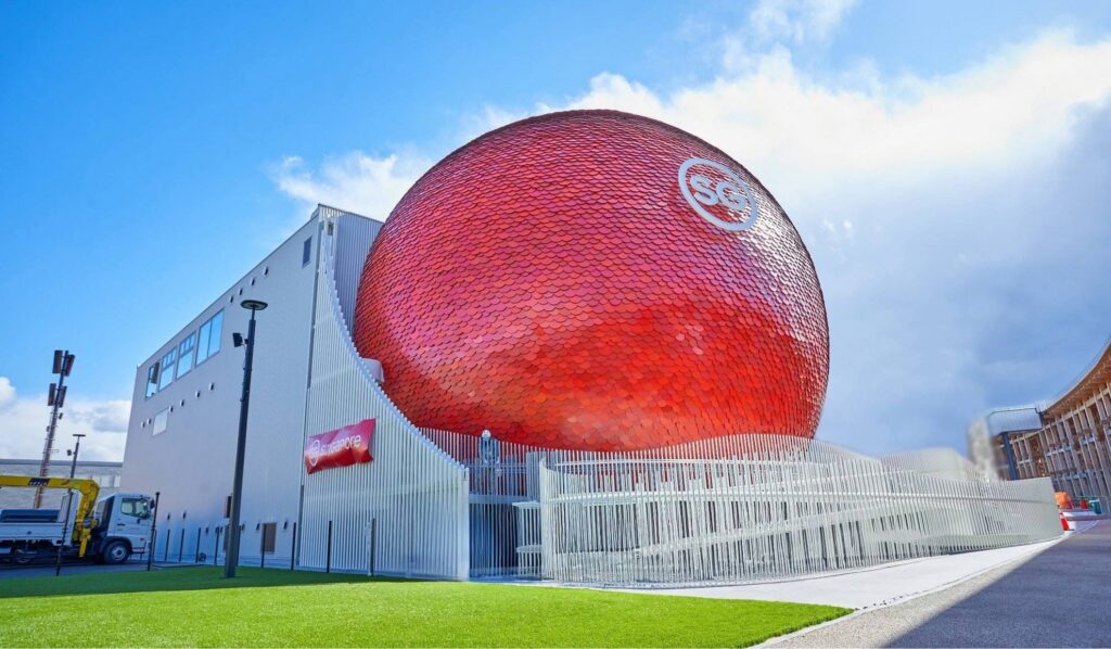 【Expo2025 Osaka】A large red sphere building with a symbol on it stands near a white building and a road